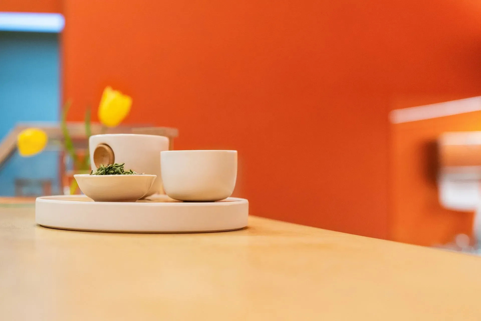 A minimal ceramic tea set with loose-leaf tea arranged on a round tray on a wooden table.