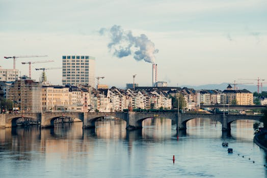 Elegante Rooftop-Bar mit Panoramablick über eine Schweizer Stadt bei Sonnenuntergang, wo Gäste an modernen Tischen sitzen und Cocktails genießen.