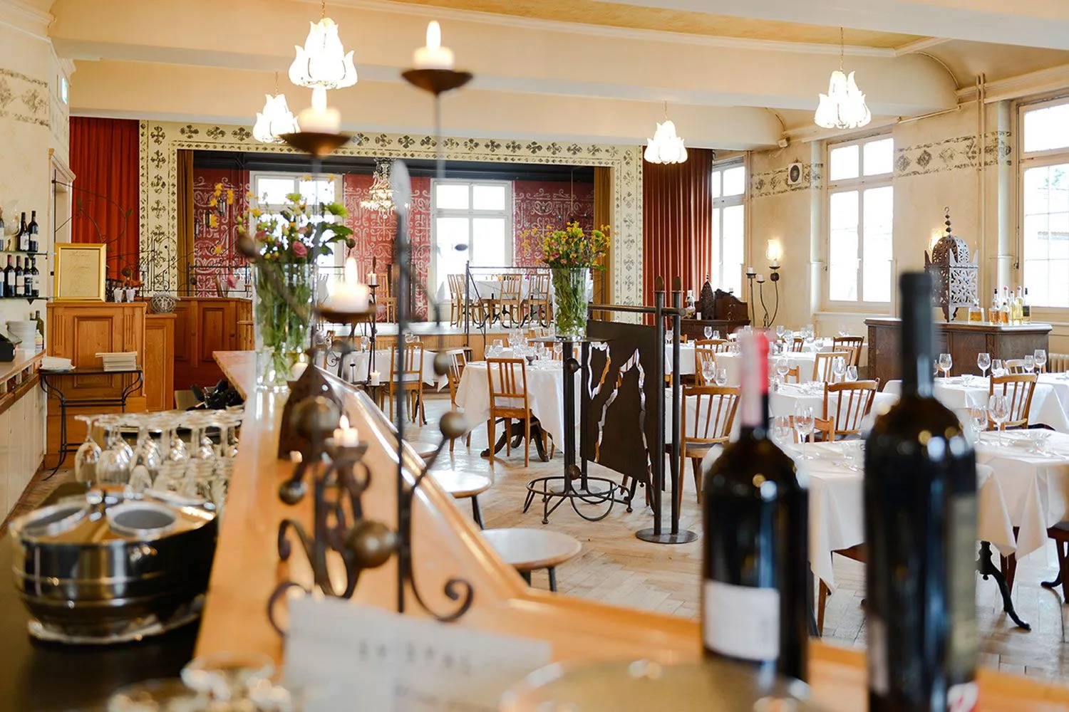 Elegant Art Nouveau dining hall with period lighting, white tablecloths, and classic architectural details showcasing the restored historic theater space.