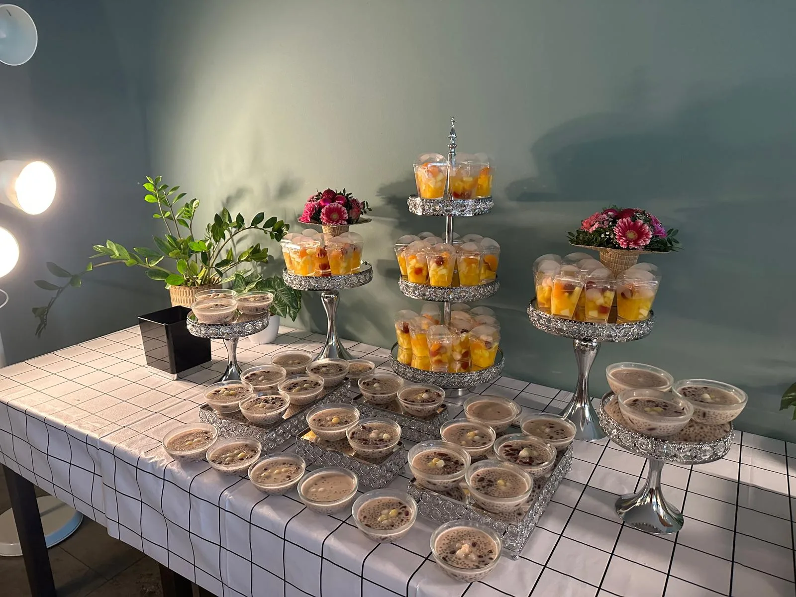 Dessert display with taro pudding cups and mango fruit cups on tiered silver stands.