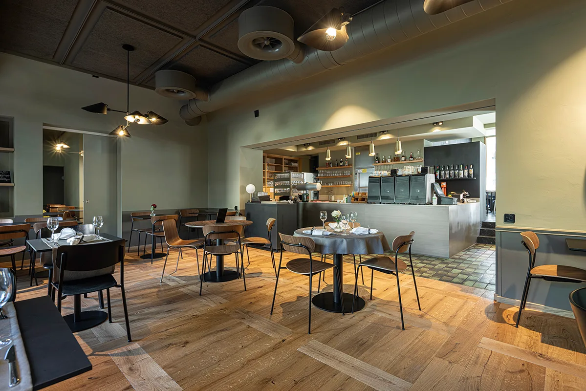 Bright red-walled dining room flooded with natural light through large windows overlooking the street outside.