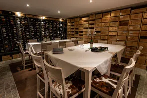 Private wine cellar dining room with floor-to-ceiling bottle storage and an intimate table setting.