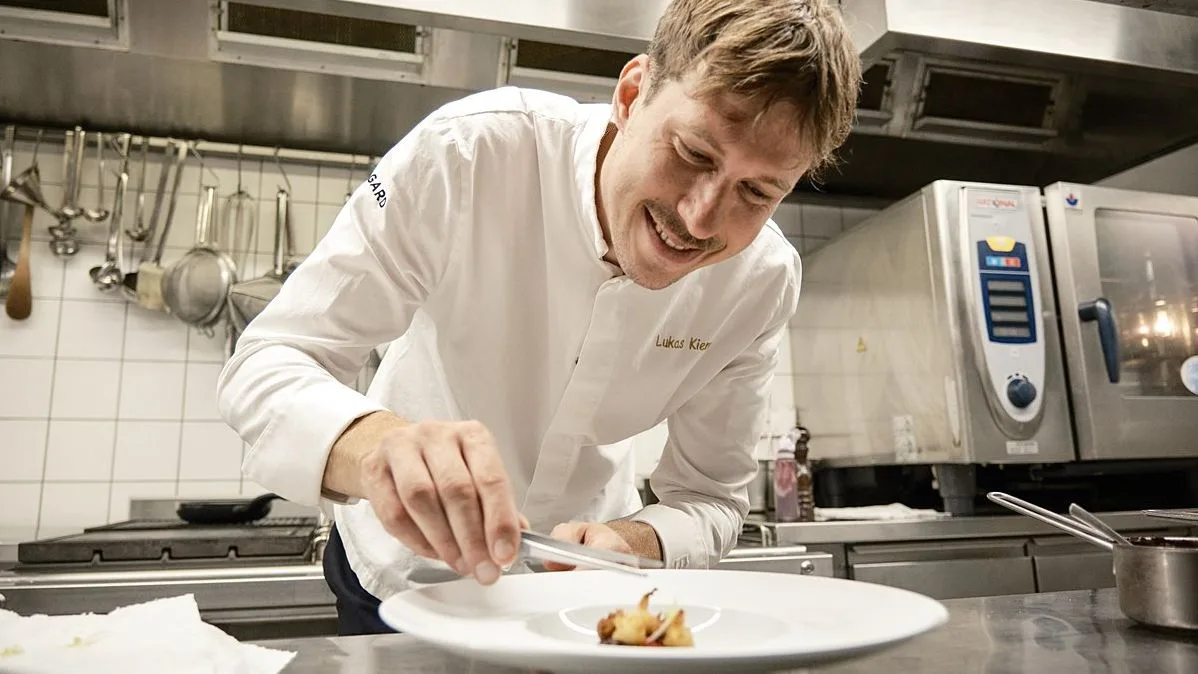 Chef Lukas Kiener plating a dish in his kitchen, embodying passion and precision in fine dining.