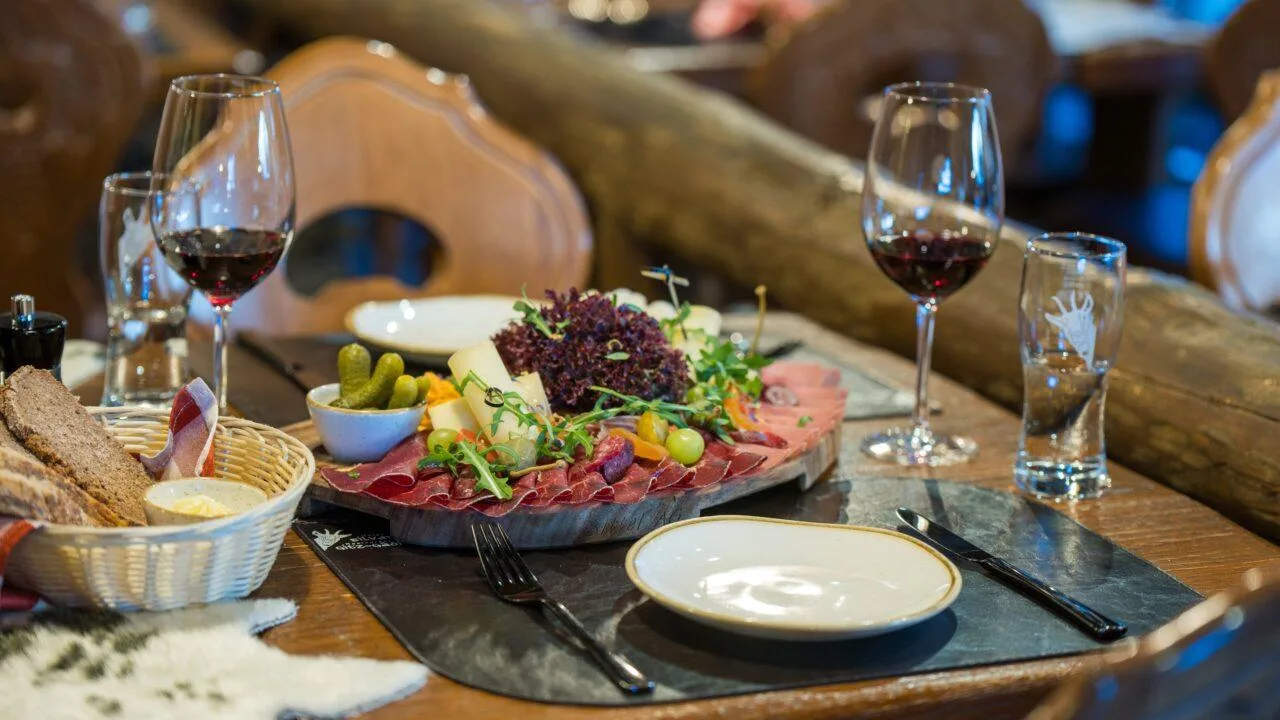 A waiter carries wine glasses beside a roaring stone fireplace in the rustic Gitz-Gädi interior.