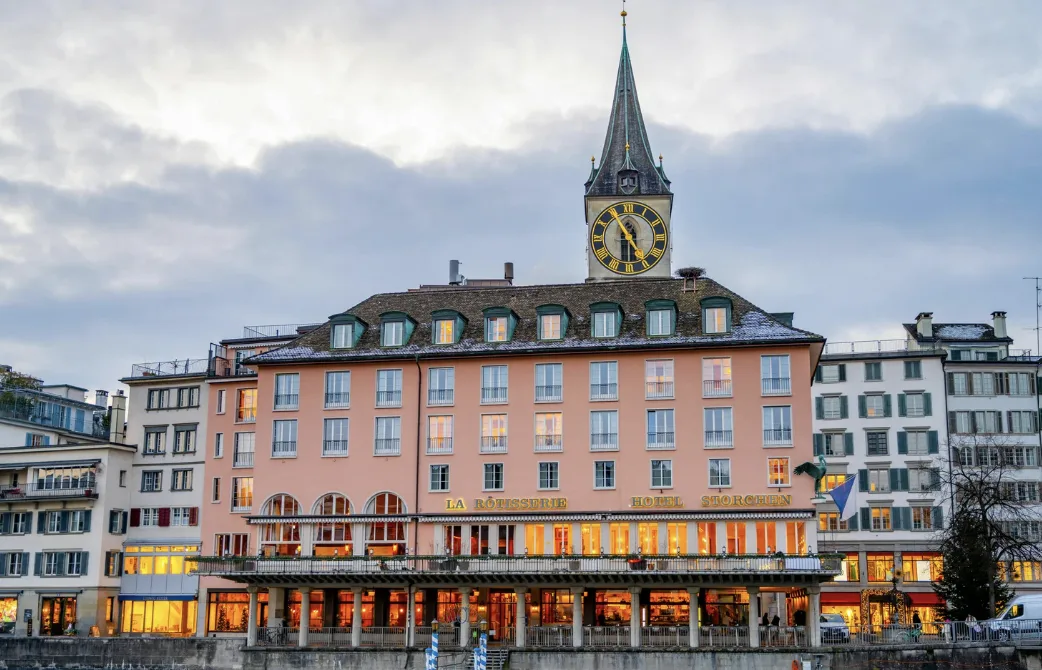 Elegant gedeckter Tisch in einem feinen Zürcher Restaurant mit perfekt präsentiertem Gourmet-Gericht und Wein vor urbaner Kulisse