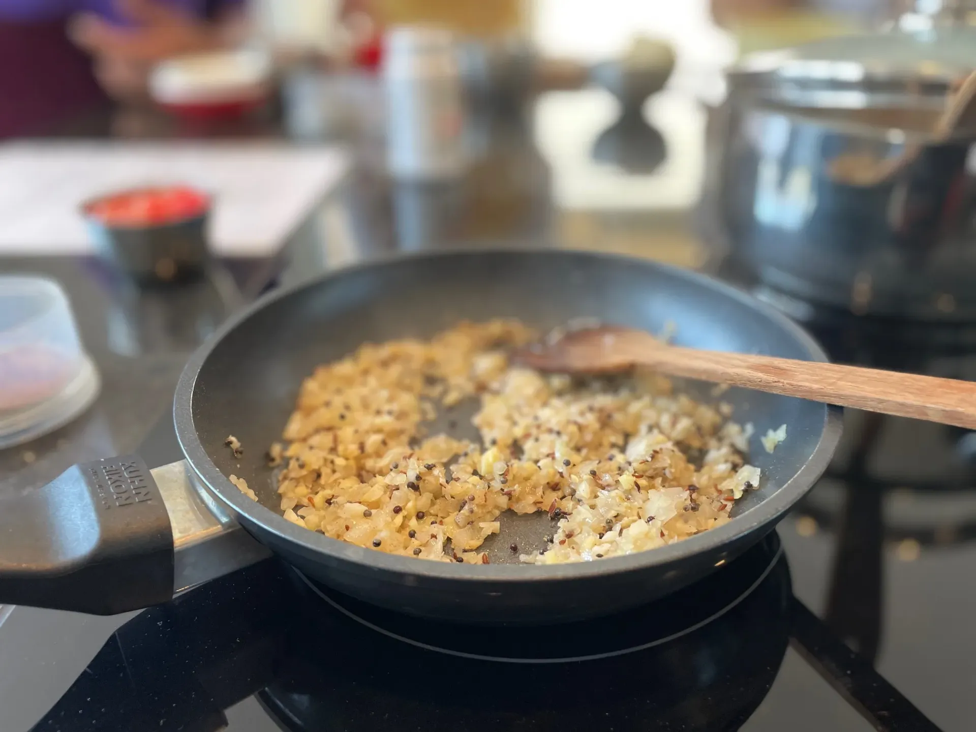 A participant carefully chops ginger and garlic on a cutting board during an Indian cooking class.