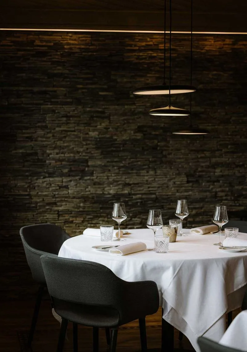 Softly lit round table set for four with crystal glasses and folded napkins in intimate dining room.