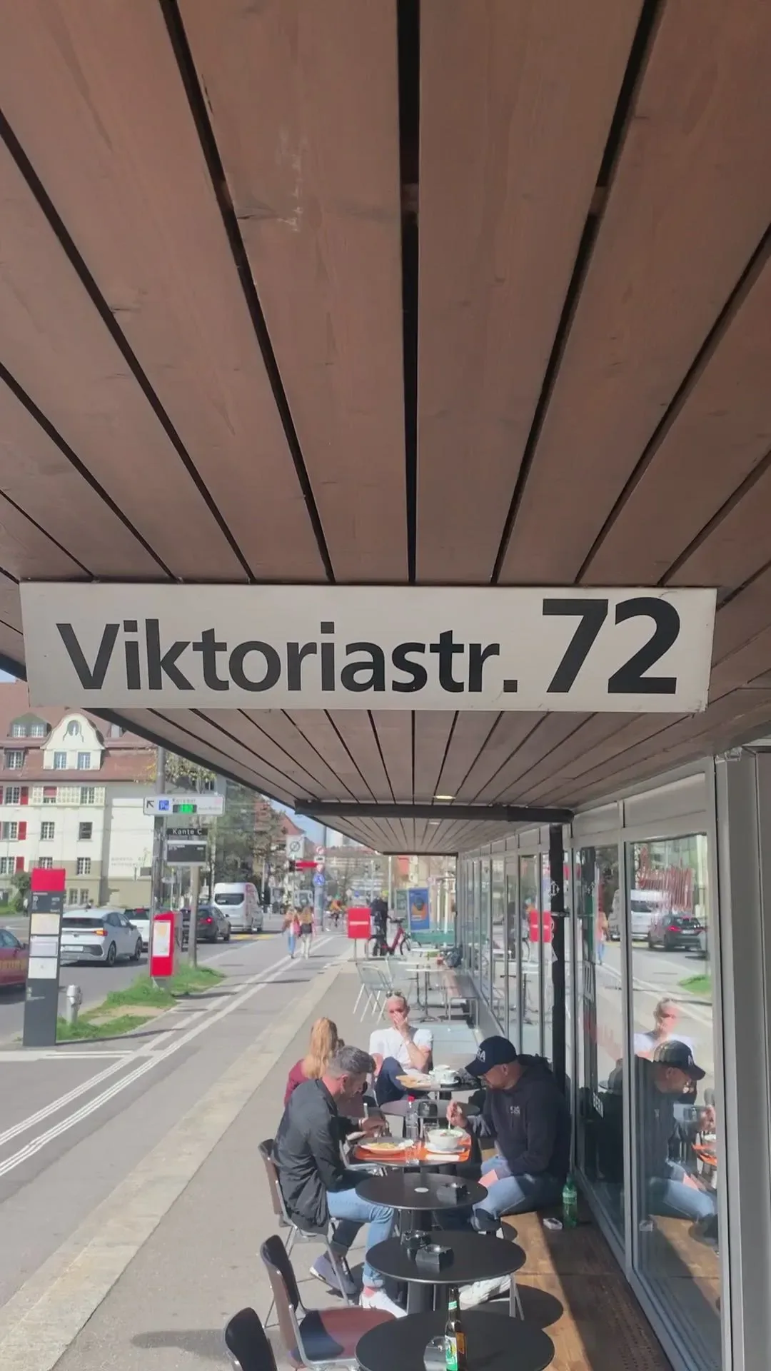 Outdoor terrace seating under a covered awning at Viktoriastrasse 72 with guests dining al fresco.