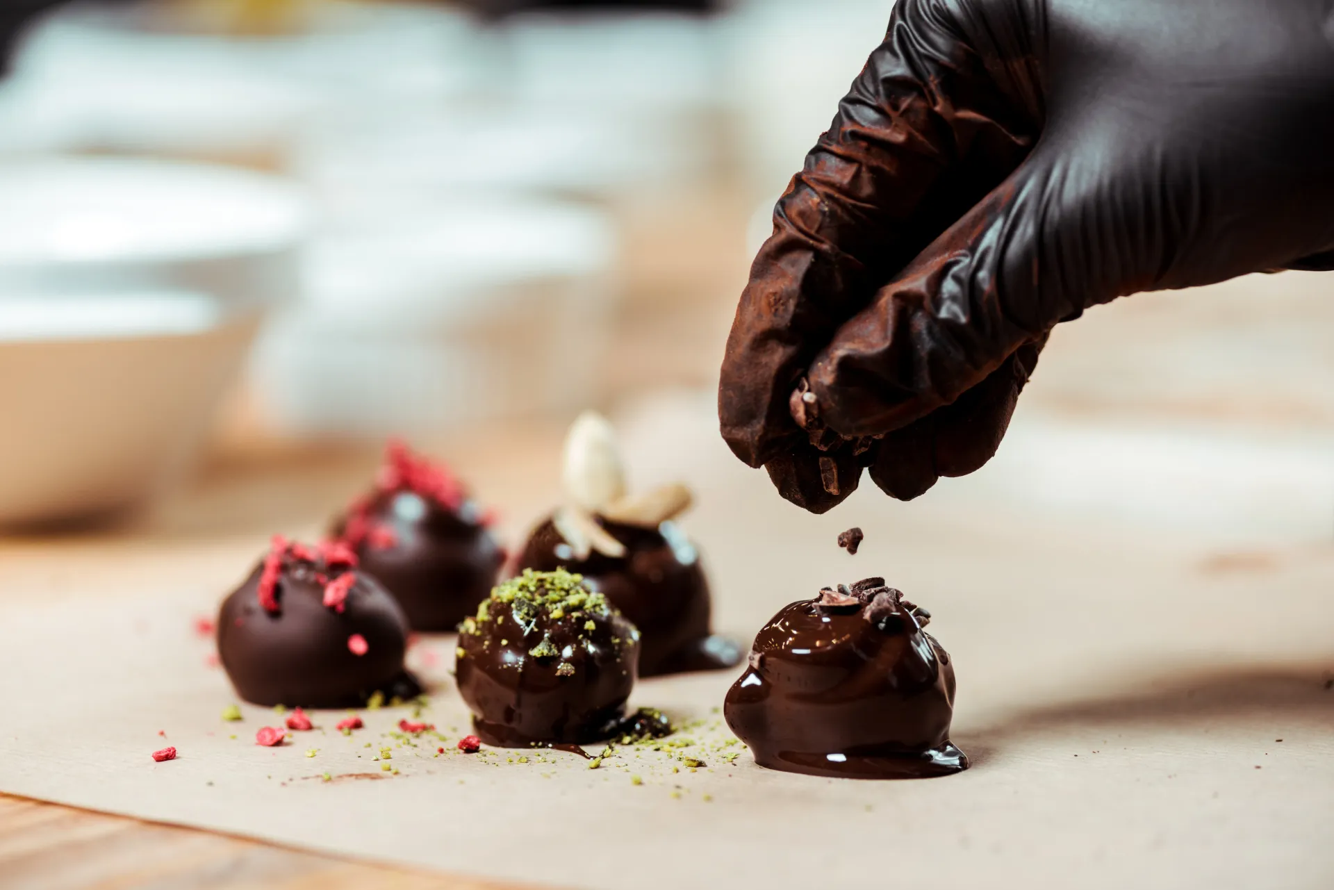 Artfully decorated chocolate truffles being hand-finished with pistachio dust—demonstrates passionate handmade production philosophy.
