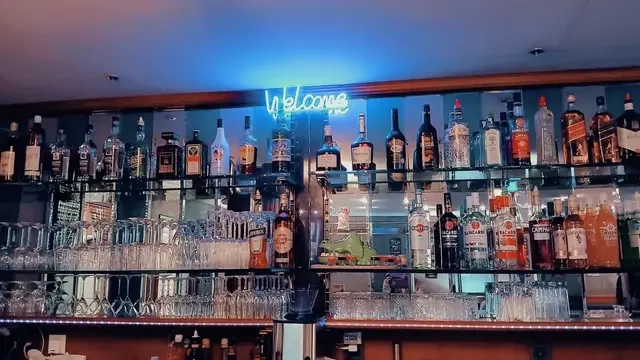 Blonde owner raises a champagne flute behind the well-stocked bar of Madame Figaro.