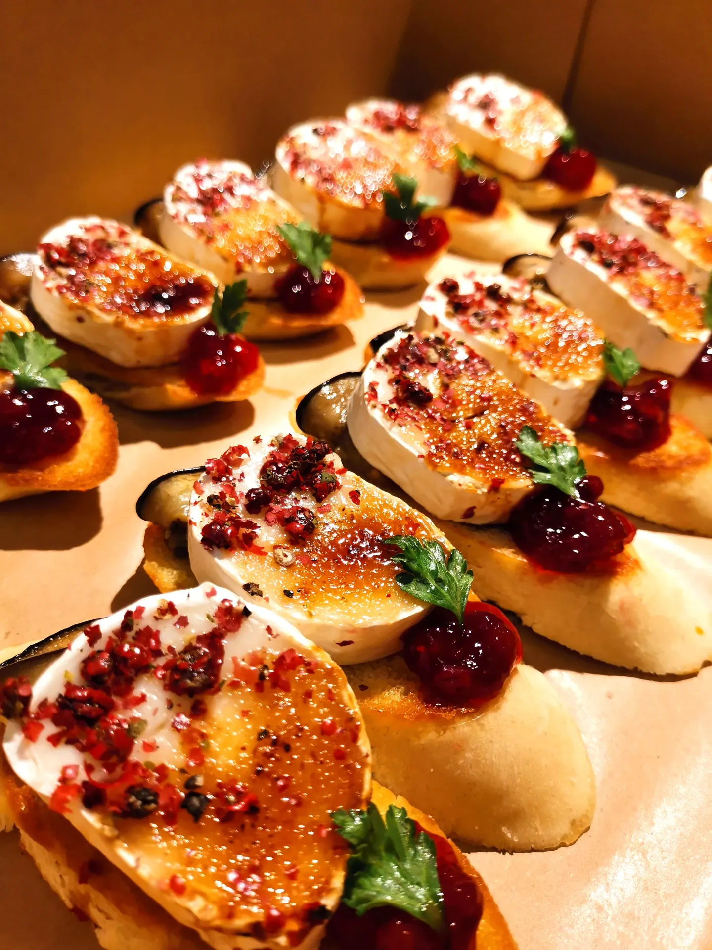 Elegant canapés of brûléed goat cheese on toast with cranberries, red pepper flakes, and fresh herbs.