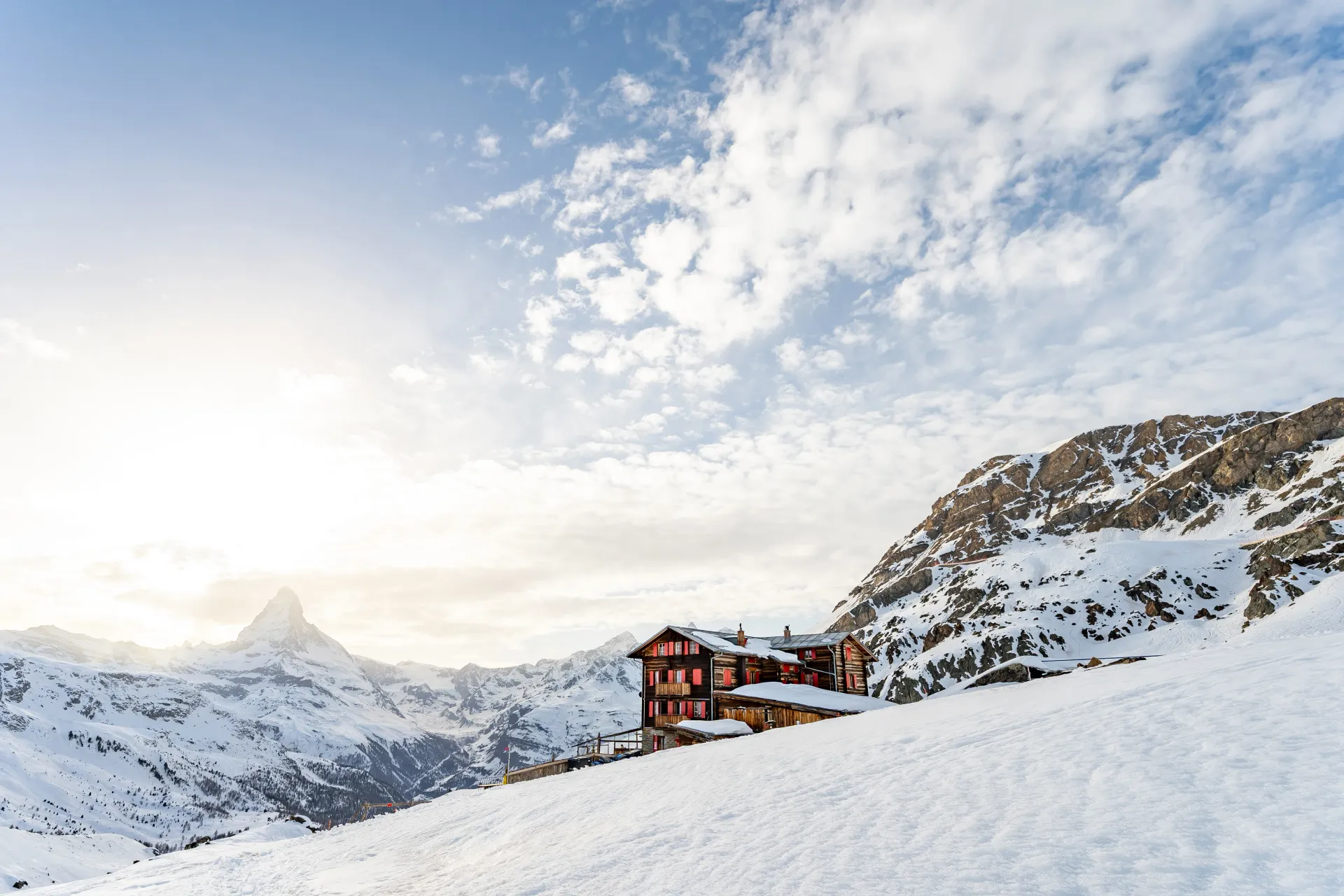 Two smiling owners pose together in front of the iconic snow-covered Matterhorn on a clear day.