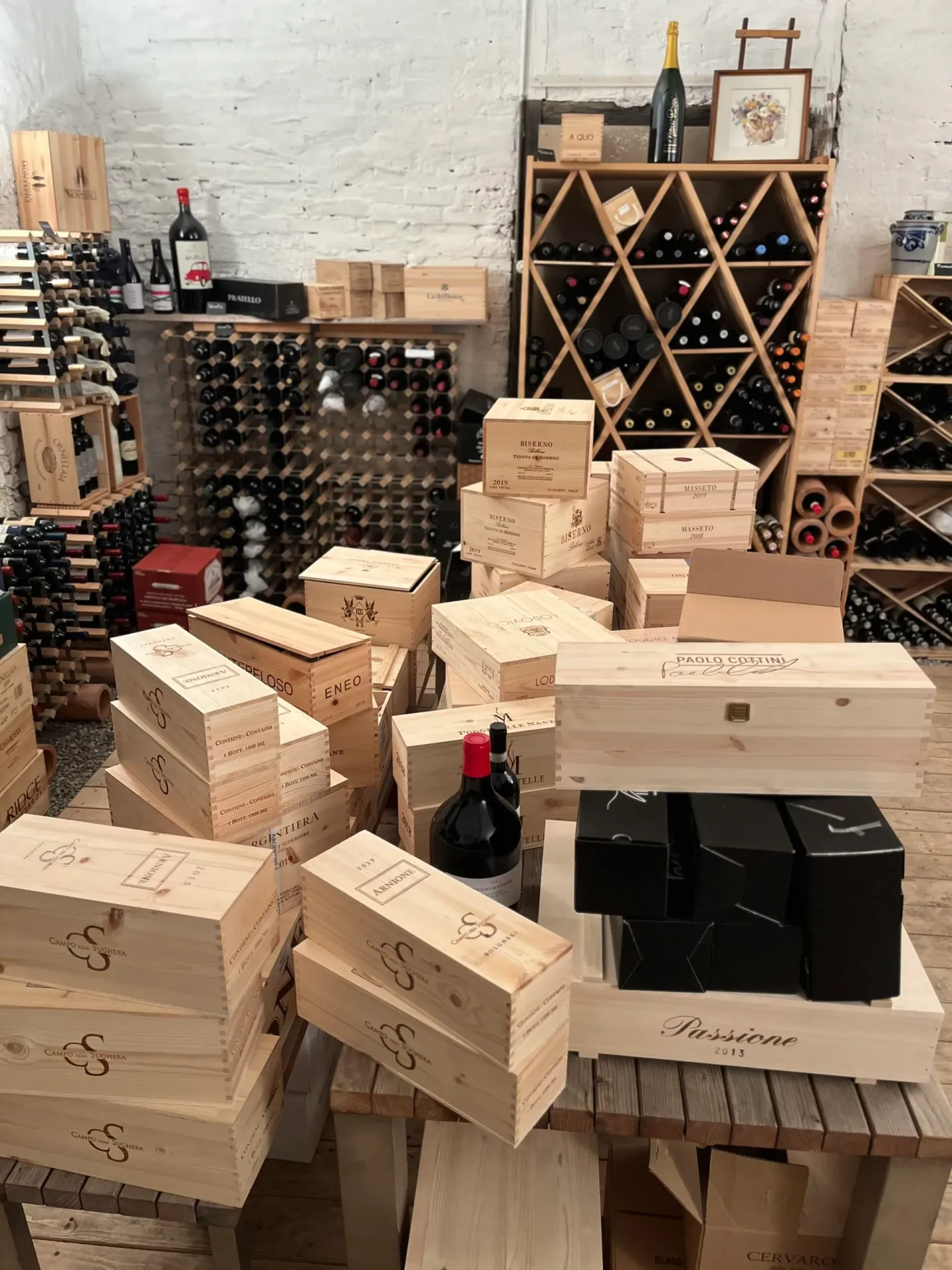 Well-stocked wine cellar with wooden crates from prestigious Italian producers including Masseto and Biserno.